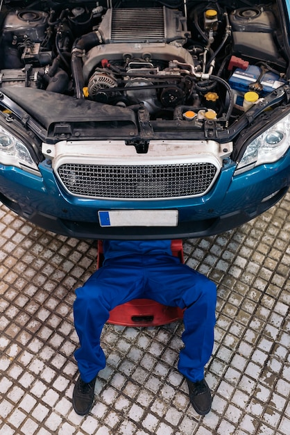 Professioneller Mechaniker, der Automotor in der Garage repariert.