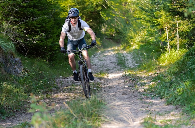 Professioneller Radfahrer, der mit dem Mountainbike bergab fährt, wirft einen Trail-Wald Abenteuersport im Freien