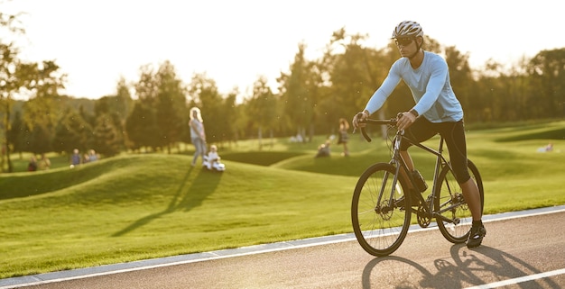 Professioneller Rennradrennfahrer, der im Freien junger athletischer Mann in Sportbekleidung und Schutz trainiert