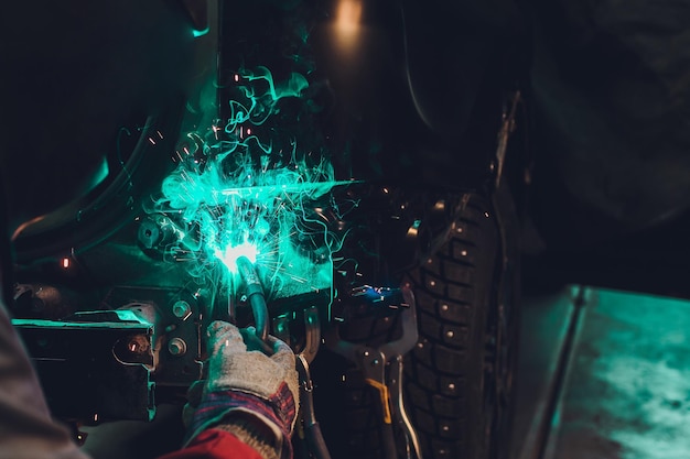 professioneller Reparaturarbeiter in der Automobilindustrie, der Metallkarosserie von Autos mit Funken schweißt