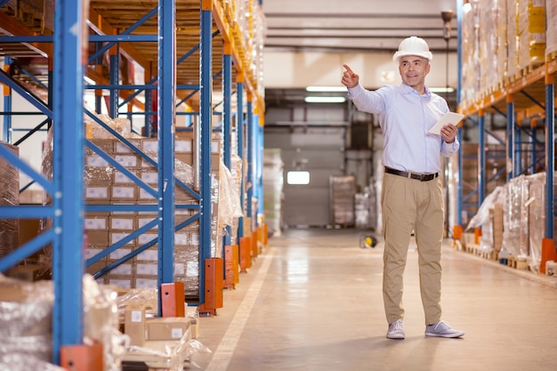 Professioneller Sicherheitsmanager, der mit seiner Hand zeigt, während er im Lager arbeitet