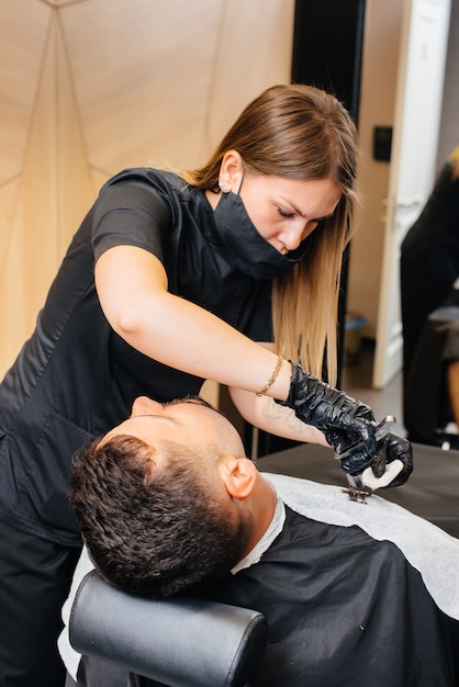 Professioneller Stylist in einem modernen, stilvollen Friseurladen rasiert und schneidet einem jungen Mann die Haare