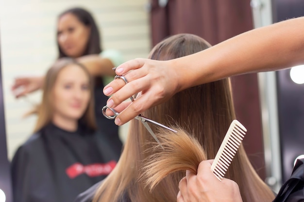 Professioneller Stylist schneidet weibliches Haar im Salon