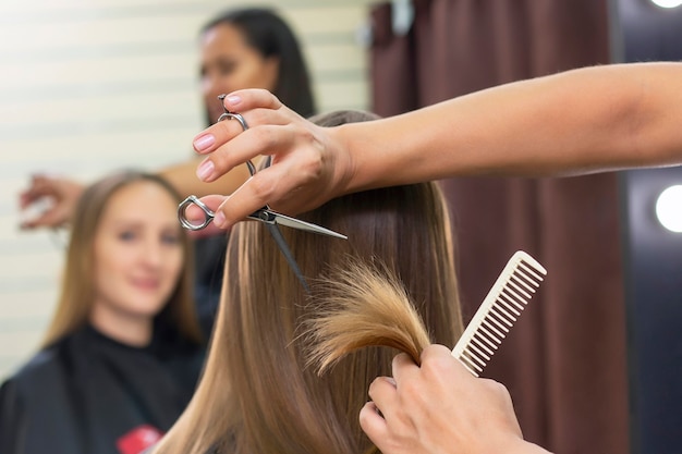 Professioneller Stylist schneidet weibliches Haar im Salon