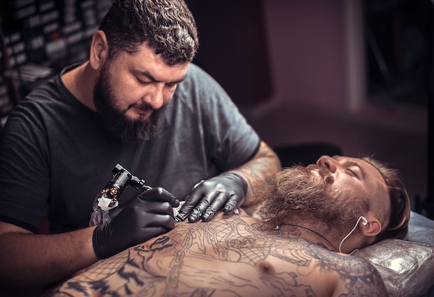 Professioneller Tätowierer, der im Tattoo-Studio tätowiert.