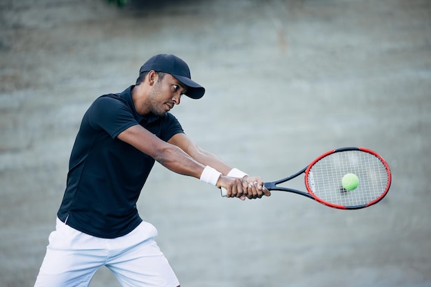 Professioneller Tennisspieler schlägt beim Spielen im Freien den Ball mit dem Schläger