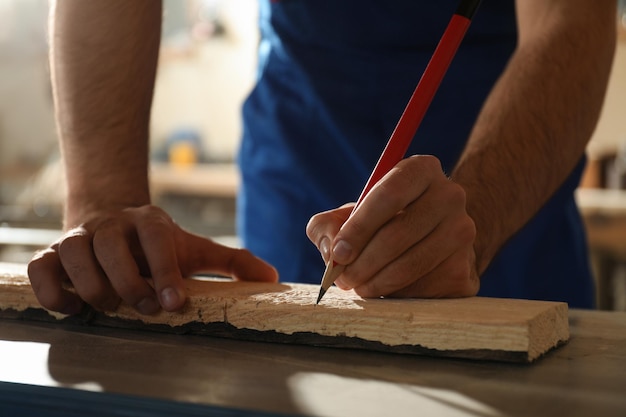 Professioneller Tischler, der in der Werkstatt Nahaufnahme auf Holzbrettern markiert