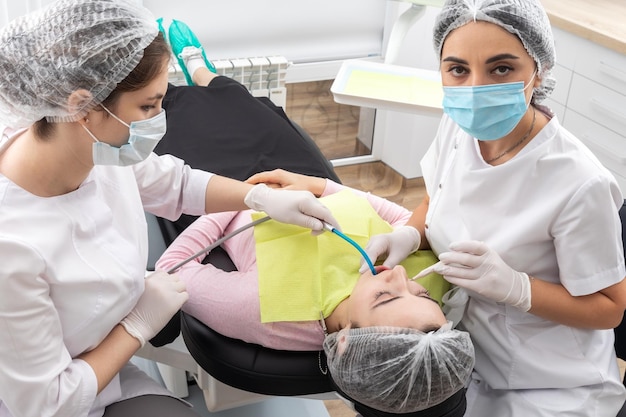 Professioneller Zahnarztchirurg und Assistent, der Zahnoperationen in einer Klinik mit moderner Ausstattung durchführt