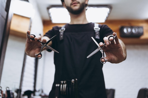 Professionelles Friseurwerkzeug geschärfte Schere, die von einem Haarschnittmeister in einem modernen Friseursalon gehalten wird