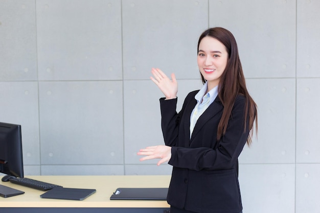 Professionelles Geschäft arbeitende asiatische Frau, die etwas trägt, während sie im Büro lächelt.