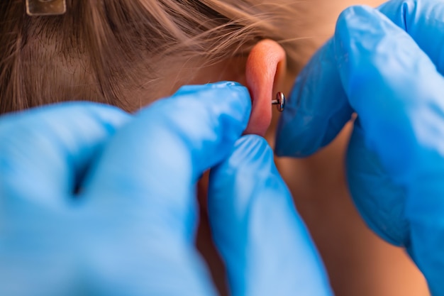 Professionelles Halten des Juwels des Piercings, kurz bevor die Kugel geschraubt wird