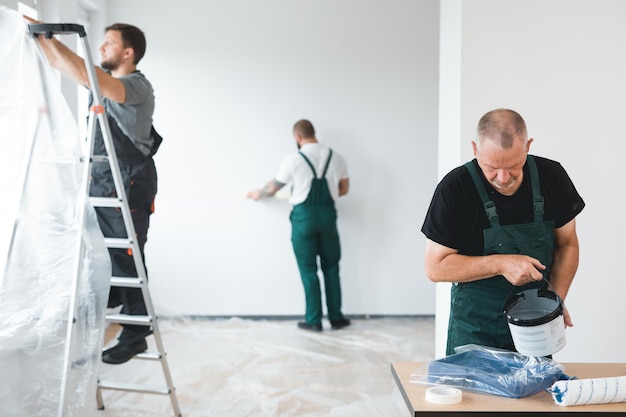 Professionelles Renovierungsteam, das die Wände der neu gebauten Wohnung streicht