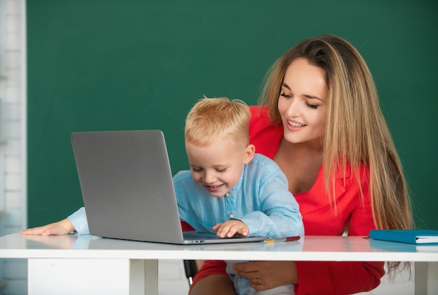 Professor ajuda crianças da escola a aprender lição usando laptop mãe e filho aprendendo