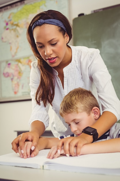 Professor ajudando um garoto com sua lição de casa na sala de aula