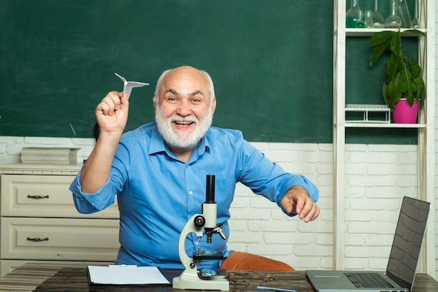 Professor barbudo na aula da escola em mesas na sala de aula Professor barbudo perto do quadro-negro na escola c