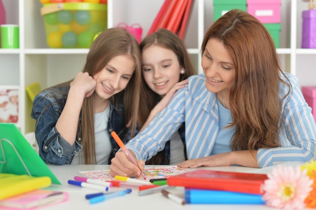 Professor com duas meninas desenhando juntos na aula de arte