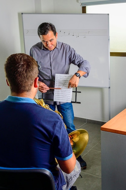 Foto professor corrige a música na sala de aula, para um jovem estudante