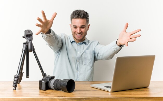 Professor de fotografia bonito jovem se sente confiante, dando um abraço para a câmera.