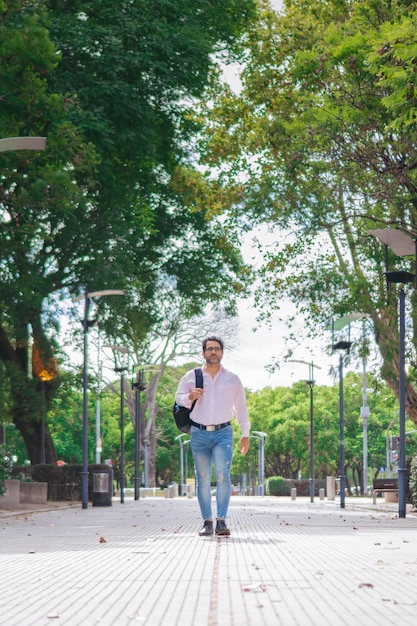 Professor de latim de meia-idade andando pelo campus da universidade com uma mochila