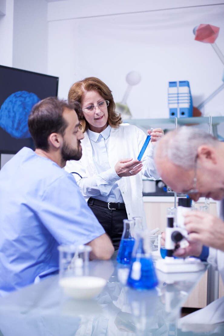 Foto professor de medicina trabalhando com microscópio no laboratório do hospital. químico trabalhando com líquidos perigosos em segundo plano.