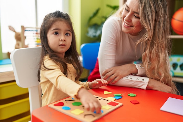 Professor e criança brincando com jogo de quebra-cabeça de matemática sentado na mesa no jardim de infância