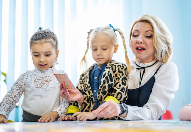 Professor e crianças brincando juntos com cartões coloridos Educação pré-escolar Método Motessori Crianças no jardim de infância Conceito de educação infantil