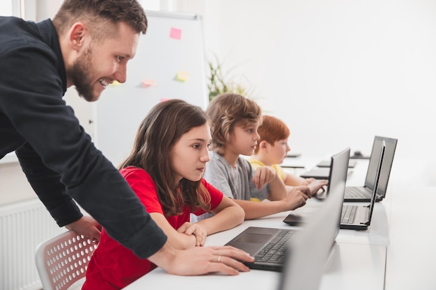 Professor e crianças tendo aulas de programação na escola