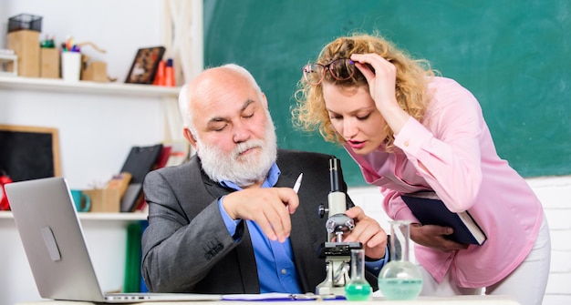 Professor e menina com bloco de notas perto do quadro-negro Biologia ciência Estudo da biologia Educação universitária Biólogo ou químico com microscópio ensinando biologia ao aluno Pesquisa biológica