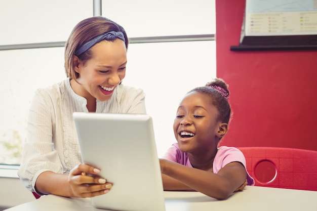 Professor e menina da escola usando tablet digital em sala de aula