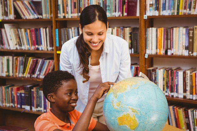 Foto professor e menino olhando o globo na biblioteca