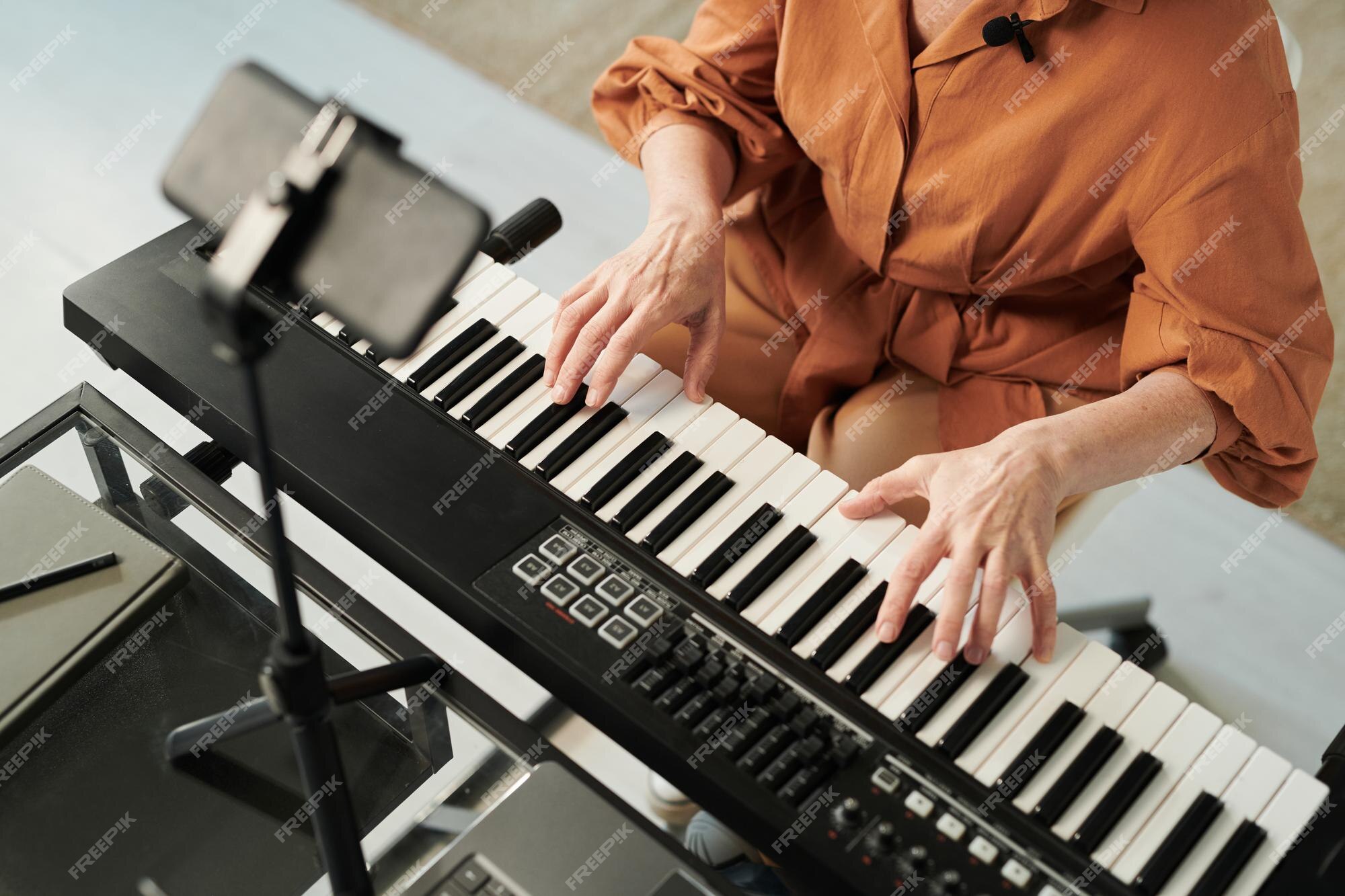 Professora ensinando seu aluno a tocar piano e gravar aula online