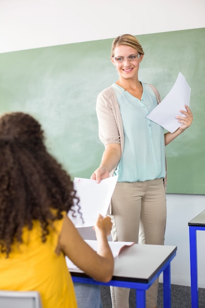 Foto professor feminino que entrega papel ao aluno