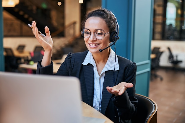 Professor internacional satisfeito gesticulando ativamente enquanto dá aula online, usando tecnologias modernas