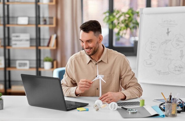 professor masculino com laptop e turbina eólica em casa