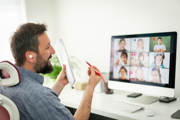 Professor masculino tendo conferência on-line com crianças em idade escolar trabalhando em casa