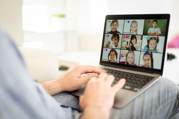 Professor masculino tendo conferência on-line com crianças em idade escolar trabalhando em casa