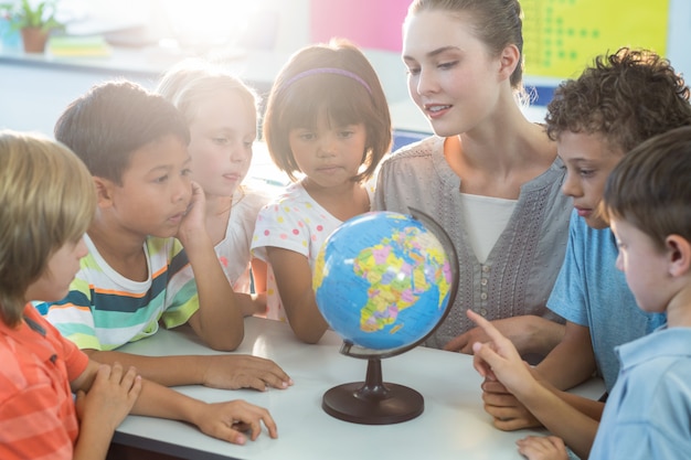 Professor, mostrando o globo para crianças em idade escolar