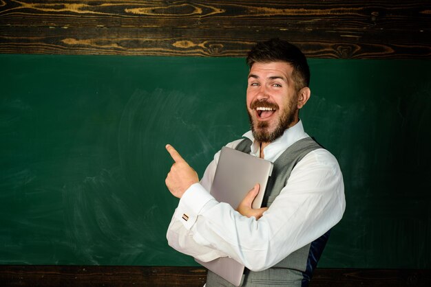 Professor no auditório perto do quadro-negro, apontando para o espaço da cópia, aluno sorridente na educação em sala de aula