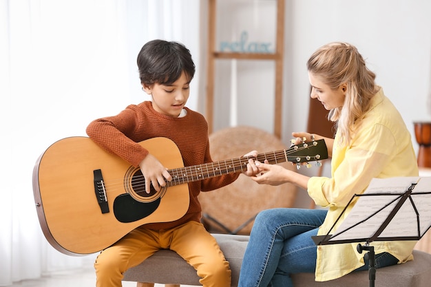 Professor particular de música dando aulas de violão para o garotinho em casa