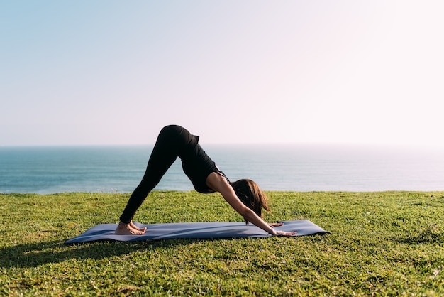 Professor praticando ioga ao ar livre em frente ao mar. Copie o espaço