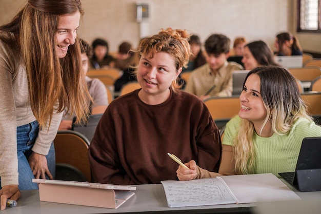 Professor resolve dúvidas individualmente para alunos em sala de aula