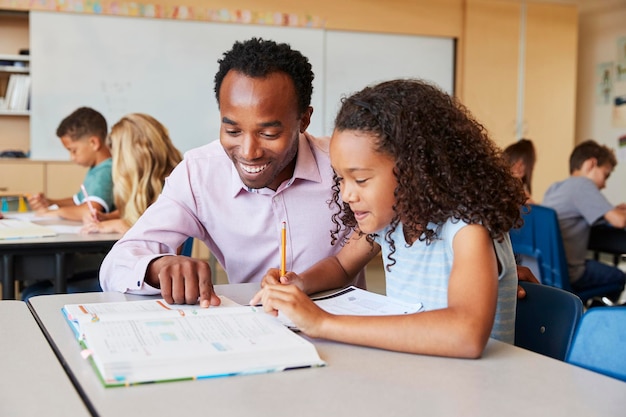 Professor trabalhando com menina do ensino fundamental em sua mesa