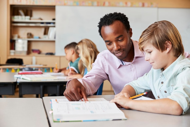 Professor trabalhando com menino do ensino fundamental em sua mesa