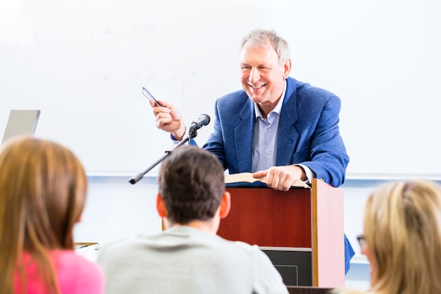 Professor universitário dando palestras para alunos sentados na mesa