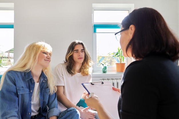 Professora conversando com dois estudantes adolescentes