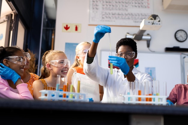 Foto professora diversificada e crianças felizes fazendo experiências na aula de química