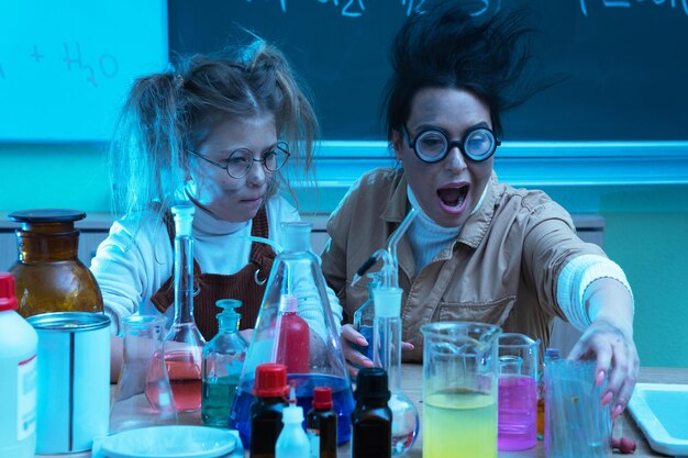 Foto professora e menina durante a lição de química misturando produtos químicos em um laboratório