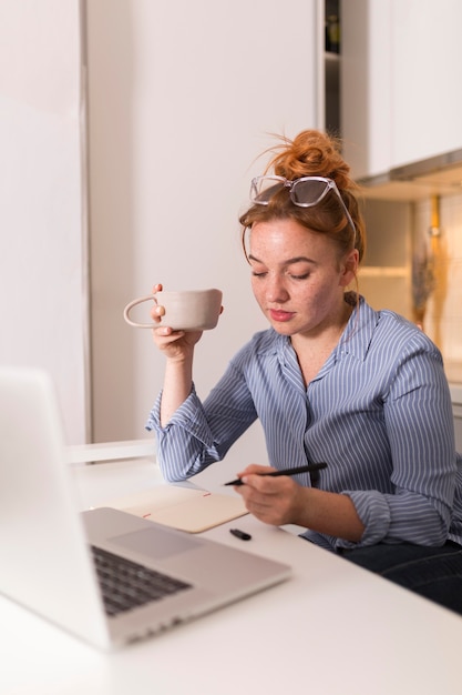 Foto professora em casa tomando chá e dando uma aula online