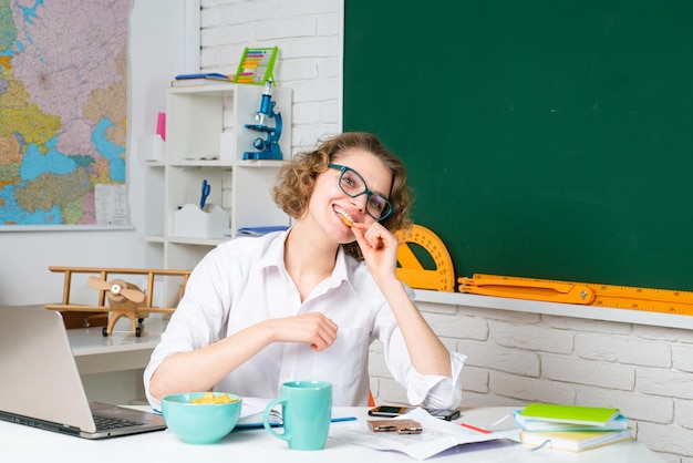 Professora em sua mesa marcando o trabalho dos alunos. professora bonita sorrindo para a câmera na escola. estudante universitário.