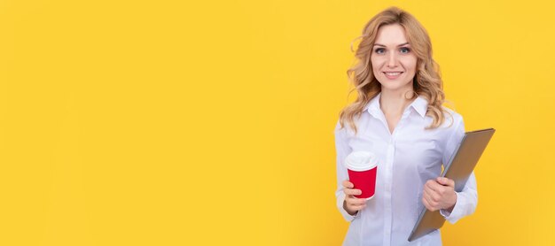 Professora feliz com laptop segurando copo de papel para viagem fundo amarelo pausa para café Mulher isolada banner de retrato de rosto com espaço de cópia simulado